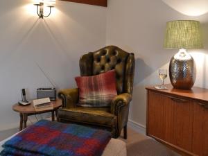 a living room with a chair and a table with a lamp at Maplehurst Barn Stables in Staplehurst