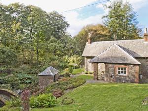 une vieille maison en pierre avec un jardin devant dans l'établissement Gardener's Cottage-Uxt, à Corsock