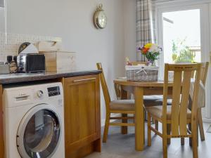 cocina con lavadora y mesa con sillas en Coastal Dream, en Burton