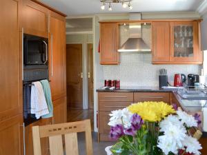 una cocina con un jarrón de flores sobre una mesa en Coastal Dream, en Burton