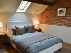a bedroom with a bed with a brick wall at Mullins Cottage in Gristhorpe +9 photos