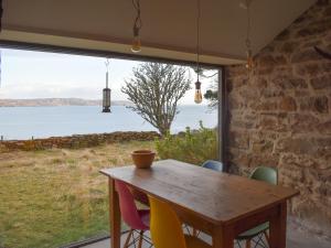 un tavolo di legno con sedie colorate e una grande finestra di Stone Cottage a Elgol