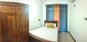 a bedroom with a bed and a wooden cabinet at Rose Apartment in Kadawata