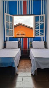 due letti in una stanza con due finestre di Hospedagem Aldeia Multiétnica a Alto Paraíso de Goiás