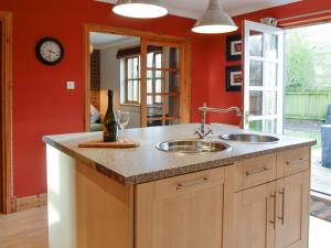 a kitchen with two sinks and a red wall at Burnbrae Cottage in Bridgend of Lintrathen
