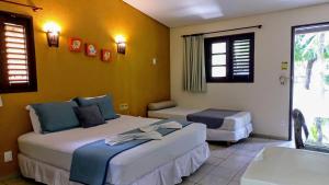 a hotel room with two beds and a window at Hotel Enseada Maracajaú in Maracajaú +230 photos