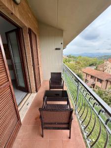 two chairs and tables on a balcony with a view at Appartamento Panoramico Urbino Vista Colline in Urbino