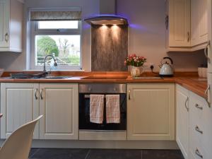 a kitchen with white cabinets and a sink at Old Orchard Cottage Near Eden in Luxulyan