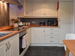 a kitchen with white cabinets and a sink at Old Orchard Cottage Near Eden in Luxulyan