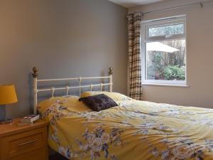 a bedroom with a bed with a yellow comforter and a window at Old Orchard Cottage Near Eden in Luxulyan