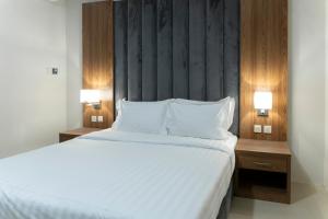 a bedroom with a large white bed with two night stands at واحة الضيافة للشقق الفندقية Wahat Aldiyafah Hotel Apartments in Buraydah