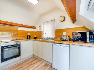 a kitchen with white cabinets and a clock on the wall at Harebell- Uk45262 in Whitby