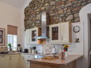 cocina con armarios blancos y pared de piedra en Ysgubor Blaenparc Barn - Uk41030, en Mydroilin