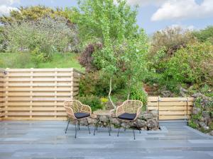 a patio with three chairs and a table and a fence at Little Foxes in Perranporth