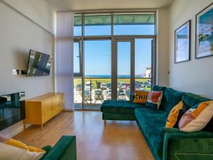 a living room with a green couch and a large window at Penthouse 47 Zinc in Newquay