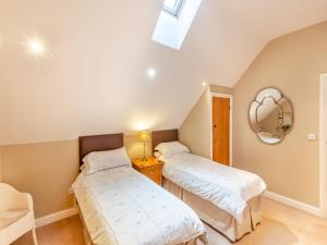 twee bedden in een kamer met een spiegel bij Oak Cottage in Ware