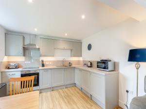 a kitchen with white cabinets and a blue lamp at Cartmel Cottage in Lindale