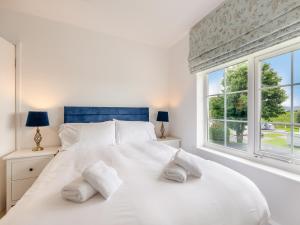 ein weißes Schlafzimmer mit einem großen weißen Bett mit zwei Kissen in der Unterkunft Cartmel Cottage in Lindale + 9 Fotos