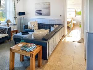 a living room with a blue couch and a table at Goleufryn in Abersoch