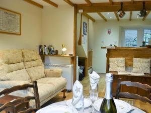 a living room with a couch and a table with a bottle of wine at Annies Cottage in Buckland Monachorum