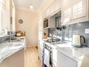 a kitchen with white cabinets and a stove top oven at Crag View in Ambleside