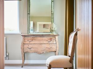 ein Spiegel auf einer Holzkommode mit einem Stuhl in der Unterkunft Carmel in Beadnell + 4 Fotos