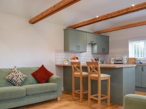 a living room with a couch and a kitchen at Brooklands Farm Cottage in Biggleswade