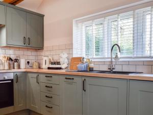a kitchen with white cabinets and a sink at Brooklands Farm Cottage in Biggleswade