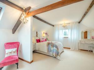 een slaapkamer met een bed en een roze stoel bij The Cottage in Arminghall