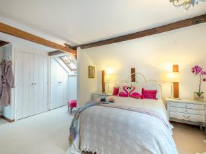 een slaapkamer met een groot bed met roze kussens bij The Cottage in Arminghall +10 foto's