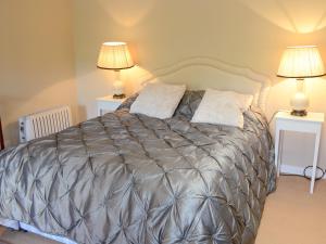 a bedroom with a bed with two lamps on two tables at Tressady Coach House in West Langwell