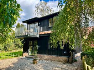 a black house with a balcony at Crown Lodge, Great Glemham in Saxmundham