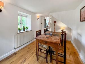 ein Esszimmer mit einem Holztisch und Stühlen in der Unterkunft Oasis Cottage in Broughton Gifford