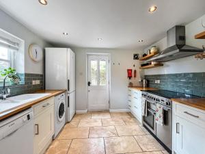 eine Küche mit weißen Geräten und Fliesenboden in der Unterkunft Oasis Cottage in Broughton Gifford