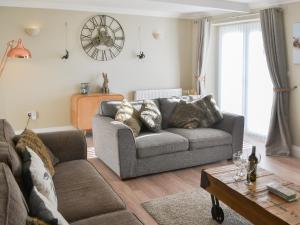 ein Wohnzimmer mit einer Couch und einer Uhr an der Wand in der Unterkunft Red Hen Cottage in Broomhill
