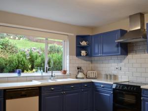 a blue kitchen with a sink and a window at Devana Croft in Tarbert