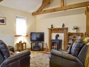 a living room with leather furniture and a wood stove at The Old Byre in Dearham