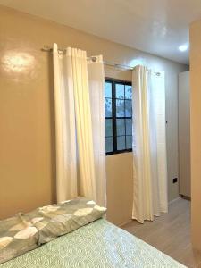 奥萨米斯A and A Transient Home in Ozamiz City的卧室配有带白色窗帘的床和窗户。