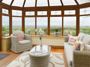 ein Wohnzimmer mit Stühlen und einem Tisch und Fenstern in der Unterkunft Barns End Cottage in Ludchurch