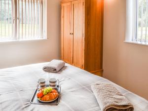 a tray with a bowl of fruit on a bed at The Pump House in Cawston