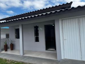 a white house with a garage at Casa em Imbituba SC, perto das Praias e Lagoa in Imbituba