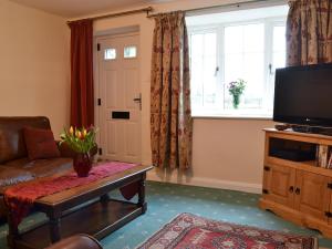 a living room with a couch and a tv and a window at Keldholme Cottage 1 - Uk10992 in Kirkbymoorside