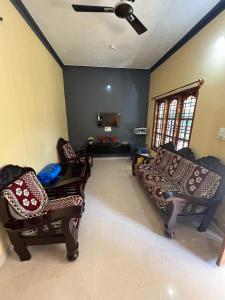 a living room with two couches and a ceiling fan at Coorg Mountain Breeze Homestay in Madikeri