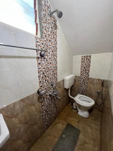 a bathroom with a toilet and a shower with a window at Coorg Mountain Breeze Homestay in Madikeri