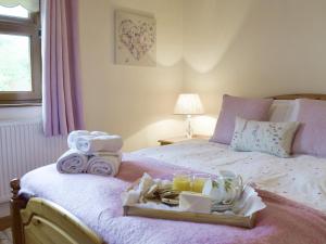 ein Bett mit einem Tablett mit Handtüchern und Getränken darauf in der Unterkunft Hayloft Cottage in Ludchurch