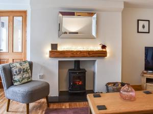 ein Wohnzimmer mit Kamin und Sessel in der Unterkunft Ivy Cottage in Dent