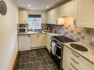 eine kleine Küche mit weißen Schränken und einer Spüle in der Unterkunft Ivy Cottage in Dent + 15 Fotos