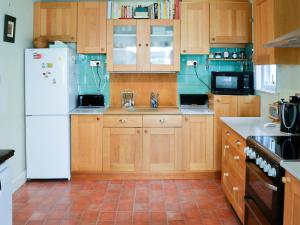 a kitchen with wooden cabinets and a white refrigerator at The Anchorage in Wroxham