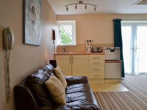 a living room with a leather couch and a kitchen at Lee Studio - Ukc3372 in West Down