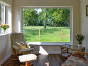 a living room with a large window and a chair at Bruno's Bothy in Wigton